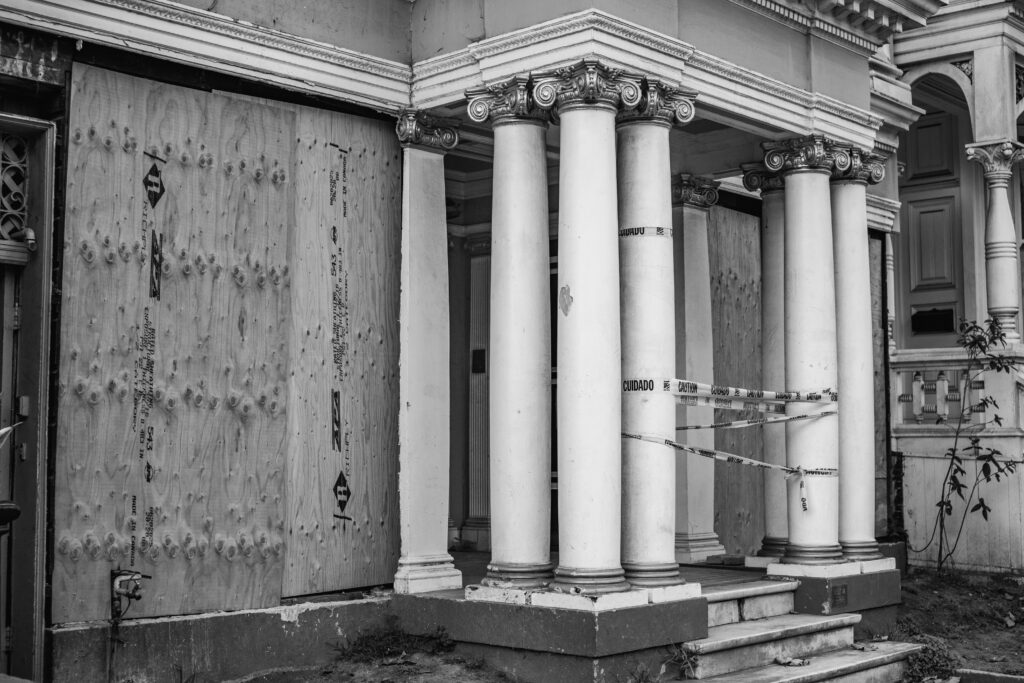 Black and white photo of an abandoned building with classical columns.